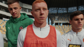 Football Must Go On TV show screenshot 3: Shakhtar Donetsk players in green, white, and orange standing together in arena.
