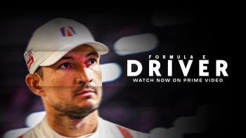 "Formula E Driver Watch Now on Prime Video" printed on a dark background with a middle aged man in a white shirt and ball cap looking off camera