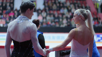 Glitter & Gold screenshot 2: Paul Poirier and Piper Gilles holding hands before stepping on the ice.