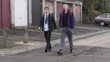 Half Man screenshot 2: Mitchell Robertson and Stuart Campbell walk down the street. Robertson wears a school uniform, Campbell wears sweatpants.