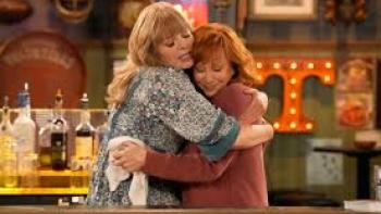 Happy's Place: Screenshot #2: Reba McEntire hugs a blond woman behind the bar