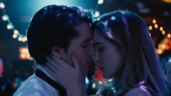 Heathers TV Series: A closeup of two teens about to kiss; behind them are colored lights such as would be found at a school dance.