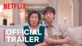 An older Asian woman and younger asian man sit side by side on a couch looking above camera with "OFFICIAL TRAILER" and "Netflix" on screen