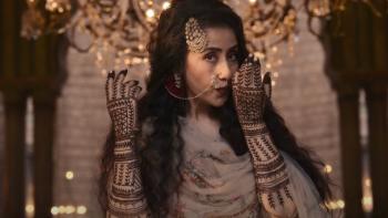 Manisha Koirala blows on the henna designs painted on both of her arms while gazing to the side.