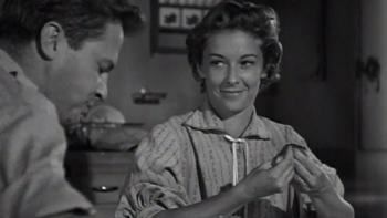 A man and woman sitting at the breakfast table, the woman is smiling.