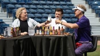 Hot Ones: Extra Heat TV show screenshot 1: Fortune Feimster and Will Ferrell clink glasses of milk as they prepare to eat hot wings