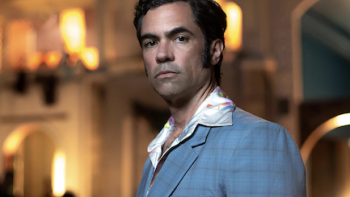 Hotel Cocaine screenshot 1: Roman Compte stands in front of well-lit building.