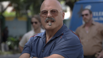 Hotel Cocaine screenshot 4: DEA Agent Zulio stands and smokes cigar with arms crossed.