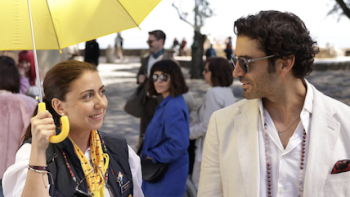 If It’s Tuesday, It’s Murder TV show TV show screenshot 1: Cristina (Carmen Ruiz) holds yellow guide umbrella talking to Fabio (Álex Garcia).