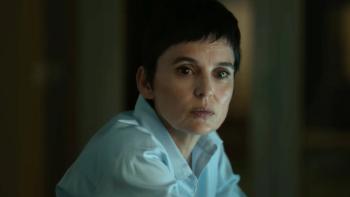 Elena Anaya sits, looking off to the side. She wears a white buttoned shirt.