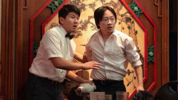 Interior Chinatown TV show screenshot 1: Fatty and Willis, dressed in waiters uniforms, stand in front of a Chinese restaurant wall, looking startled