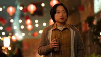 Interior Chinatown TV show screenshot 3: Willis stands on a city street with lights strung behind him; he is looking into the distance