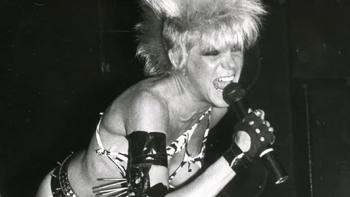 nto the Void TV show screenshot 3: Wendy O. Williams of the band Plasmatics sings into a mic while wearing a zebra-print bikini and punk rock hairdo