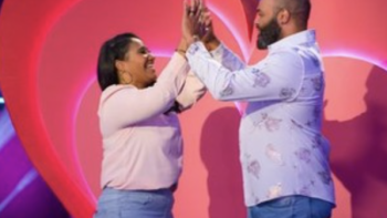 Is it Cake? Valentine's TV show screenshot 3: A couple double high fives each other in front of a giant heart. 