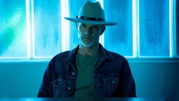 Justified: City Primeval: Raylan Givens sits at a desk in his cowboy hat, silhouetted against bright blue neon lights that give the image an eerie blue tinge. 