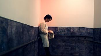 Knife Edge: Chasing Michelin Stars TV show screenshot: An Asian chef stars at the floor staring down at the floor standing in an empty room.