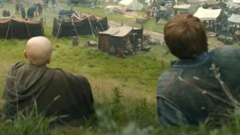 A Knight of the Seven Kingdoms TV show screenshot 3: Egg and Dunk sit on a hillside, looking down upon a humble village in a green valley