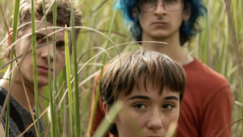 La chica invisible TV show screenshot 2: Ivan, Julia, and Emi watch from a grassy field. 
