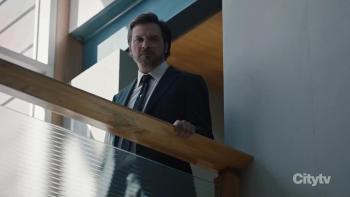 Law & Order Toronto: Criminal Intent: Aden Young looks over a balcony in a corporate building.