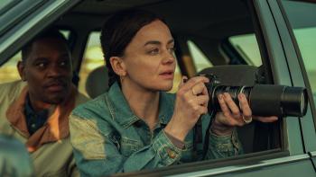 Legends TV show screenshot 3: Aml Ameen and Hayley Squires sit in a car. Squires points a camera out the passenger window. She wears a denim jacket.