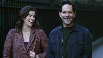 Living with Yourself Series: Kate and Miles grin happily as they stand together in an outdoors shot. 