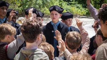 Lord of the Flies TV show screenshot 3: Jack and the rest of the chorus wears their hats and robes; the other survivors are all staring at the chorus