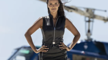 Love Island Games TV show screenshot 1: Maya Jama in black leather on beach in front of helicopter.