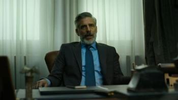Maledictions TV show: A man in a business suit sits behind a desk in front of curtains in an office.
