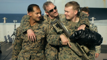Marines TV show screenshot 3: Marine snipers in fatigues hug while holding rifles. 