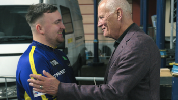 Matchroom: The Greatest Showmen TV show screenshot 3: Barry Hearn embraces a star dart thrower in blue uniform. 