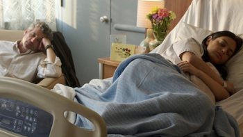 Memory of a Killer TV show screenshot 3: Maria rests in hospital bed with Angelo asleep in chair next to her.