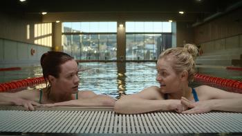 MILF of Norway TV show screenshot 1: Kikka and Lene are in a lap pool, arms out and holding the edge of the pool. 