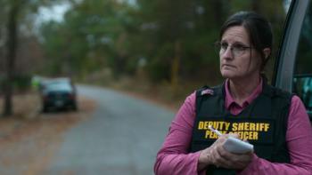 Missing; Dead or Alive: A woman writes on a notepad while standing in the woods and wearing a vest that says Deputy Sheriff Peace Officer