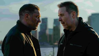(From L-R) Tom Hardy and Paddy Considine stand against a city skyline. They both wear dark jackets.
