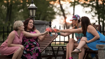 Mohawk Girls TV Show: Zoe and Caitlin sit across from Anna and Bailey on lawn chairs, toasting pink cocktails.
