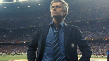 Mourinho TV show screenshot 1: José Mourinho in a suit stands confidently on a soccer field, stadium lights shining behind.