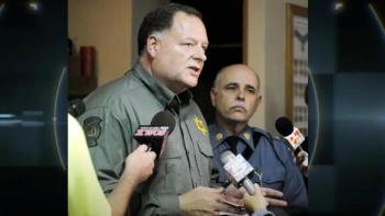 Murder 360 TV show screenshot: A police sheriff is giving a press conference with microphones being held towards him.