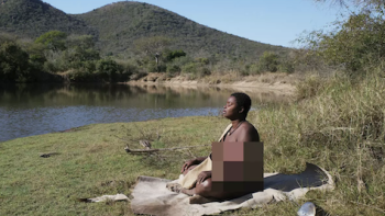 Naked and Afraid: Solo: Shanika Malcolm is a Black-Indigenous woman sitting on blanket facing the sun.