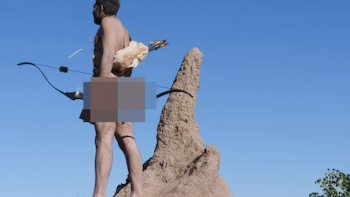 Naked and Afraid: Solo: Fernando Calderon stands with bow and arrows next to pointed rock and looks out left. 