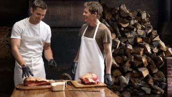No Taste Like Home with Antoni Porowski TV show screenshot 3: Porowski and James Marsden wear aprons while standing at a table laden with raw meat