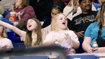 Not Her First Rodeo TV show screenshot 3: A rodeo crowd, fronted by two excited little girls, cheers on the bull rider
