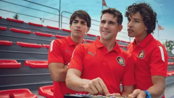 O11CE New Generation TV: Ricky, Gabo and Dedé wearing Hawks jerseys stand in front of the stands watching something off screen.