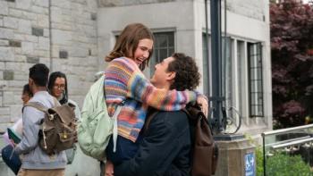 Off Campus TV show screenshot 1: Garrett lifts Hannah into the air in front of a college building; both are smiling delightedly