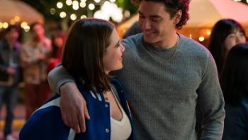 Off Campus TV show screenshot 2: Garrett puts his arm around Hannah in a party scene; a string of lights and party guests appear behind them
