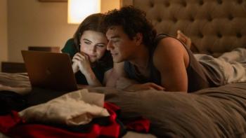 Off Campus TV show screenshot 3: Hannah and Garrett lie on their stomachs together on a bed, looking at something on a laptop computer
