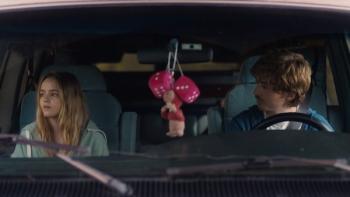 Penelope and Sam sit in the front seat of Sam's van, a set of pink fuzzy dice hang from the rearview mirror