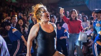 The Queen of Villains screenshot 1: Dump wears a black leotard shaking he hair and shouting while standing in the audience at a wrestling show