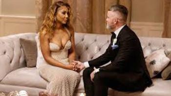 Queens Court TV show: A black woman in a formal dress sits on a couch holding hands with a white man wearing a tuxedo.