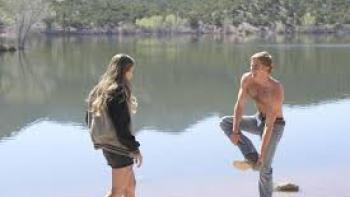 Ransom Canyon TV show screenshot #2: A young White man and woman stand by a lake; he has his shirt off