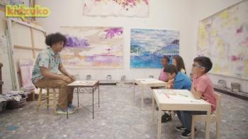 Reading Rainbow TV show screenshot 2: Mychal the Librarian sits opposite three young kids in desks in an art room.